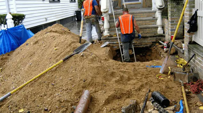 Contractors performing foundation protection and exterior drainage excavation near residential home steps in New Orleans, LA