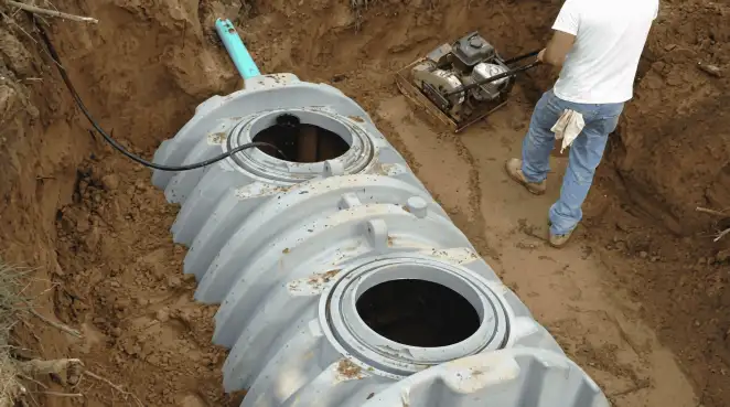 Septic tank installation showing a technician compacting soil around a new poly septic tank in an excavation pit in New Orleans, LA
